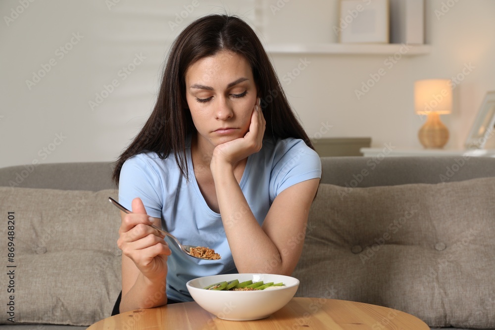 Eating disorder. Sad woman holding spoon with granola over bowl indoors Eating disorder. Sad woman holding spoon with granola over bowl indoors