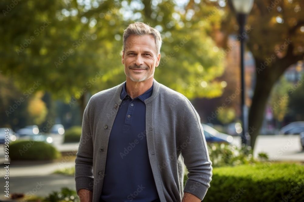 Portrait of a tender man in his 40s wearing a chic cardigan isolated on vibrant city park Portrait of a tender man in his 40s wearing a chic cardigan isolated on vibrant city park