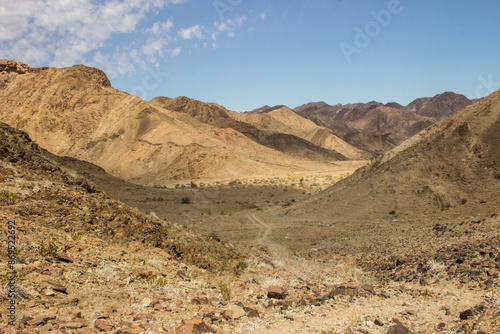 A small twee track road winding through the barren and rocky environment within the Fish River Canyon in Namibia