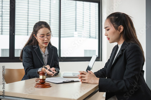 Young Lawyer Advising a Young Woman in a Modern Office Setting with Legal Documents and Gavel on Desk