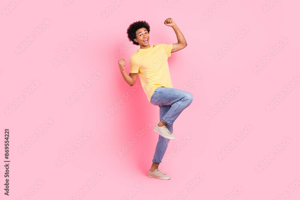Full length photo of cute lucky guy dressed yellow t-shirt screaming rising fists isolated pink color background Full length photo of cute lucky guy dressed yellow t-shirt screaming rising fists isolated pink color background