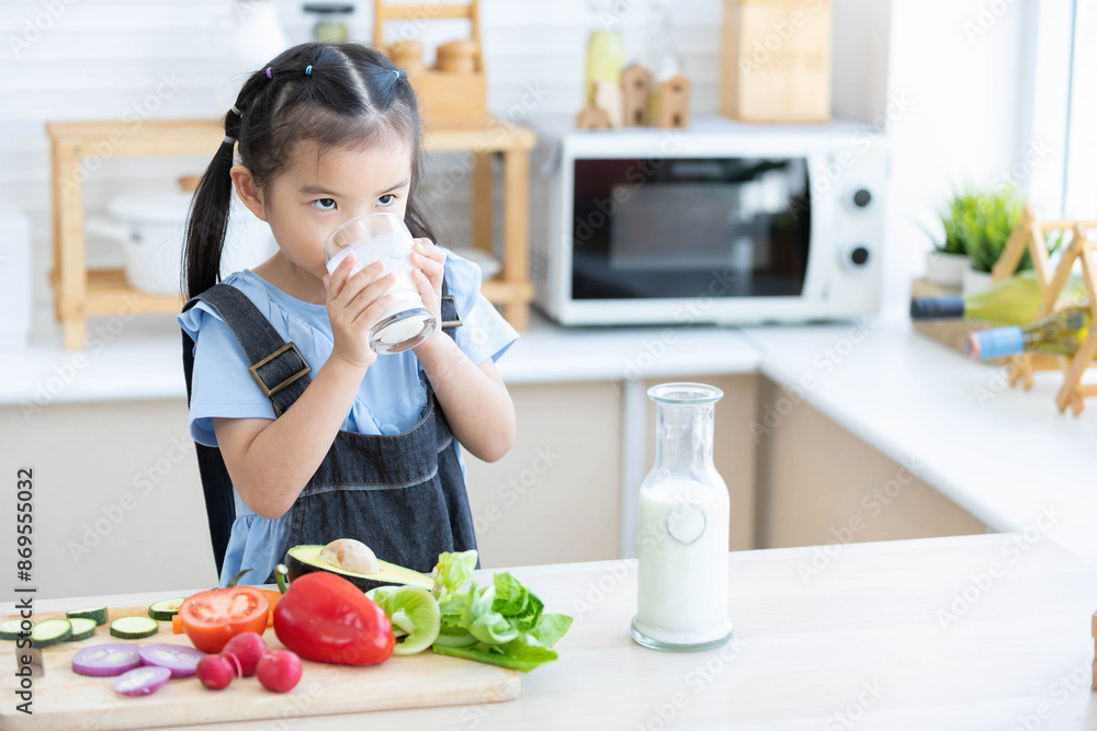 cute asian little child girl drinking milk in the kitchen