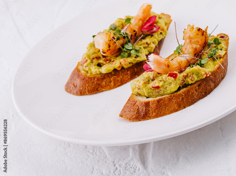 Gourmet shrimp avocado toast on white plate Gourmet shrimp avocado toast on white plate