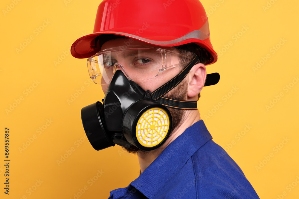 Man in respirator mask and hard hat on yellow background Man in respirator mask and hard hat on yellow background