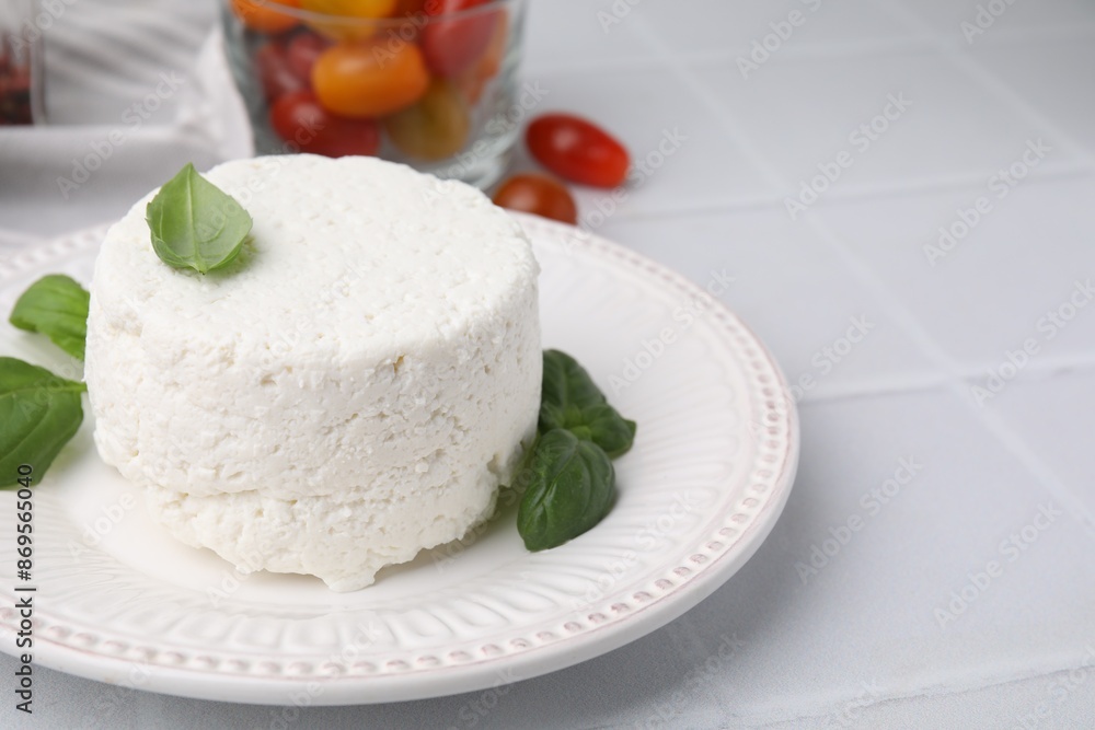 Fresh ricotta (cream cheese) and basil on light tiled table, closeup. Space for text Fresh ricotta (cream cheese) and basil on light tiled table, closeup. Space for text
