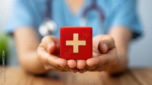 Nurse in blue scrubs holding a red cube with a medical cross, highlighting healthcare and support