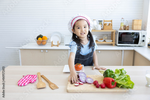 asian kid cooking and preparing vegetables meal in the kitchen