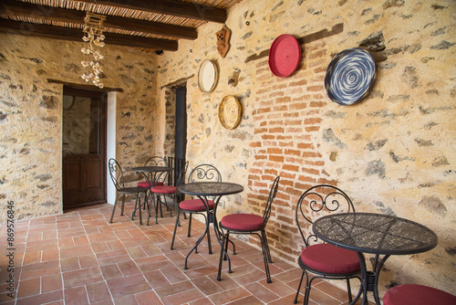 Garden and terrace design or landscaping:Rustic wrought iron tables and chairs on a natural stones terrace or patio decorated with braided straw baskets-traditional handcraft, Sardinia, Italy
