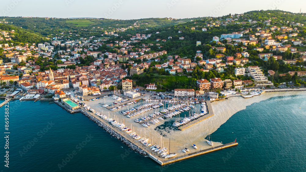 Obraz premium An aerial sunset view of the charming town of Muggia in Friuli Venezia Giulia, Italy with white mucilaginous blooms blanket. This picturesque town, located near the border with Slovenia 
