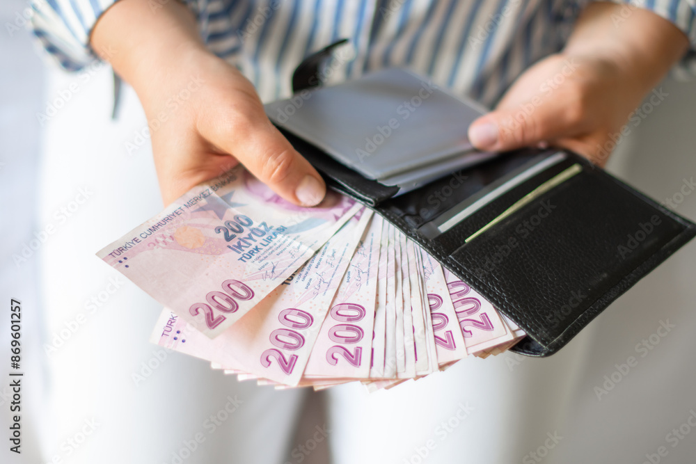Leather wallet with money in the hands of a woman. Close-up of a woman taking a Turkish lira with a fan from her wallet, a lot of money but little value,high inflation rate in Turkey Leather wallet with money in the hands of a woman. Close-up of a woman taking a Turkish lira with a fan from her wallet, a lot of money but little value,high inflation rate in Turkey