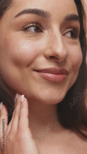 A detailed close-up capturing a woman touching her flawless skin, embodying a natural beauty concept.