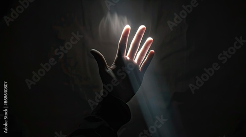 Single hand emerging from darkness, illuminated photo