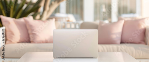 A white MacBook sits on a table in front of a couch with pink pillows by AI generated image