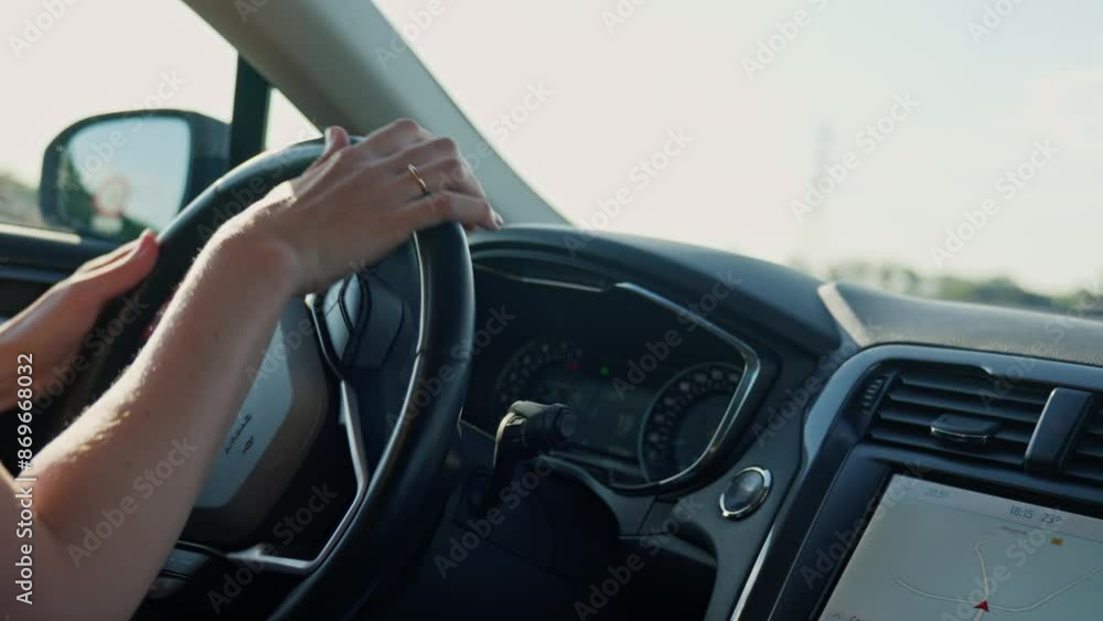 Close up view of female driver hands on steering wheel. Woman driving car at sunset. Inside view of modern vehicle moving on road Close up view of female driver hands on steering wheel. Woman driving car at sunset. Inside view of modern vehicle moving on road