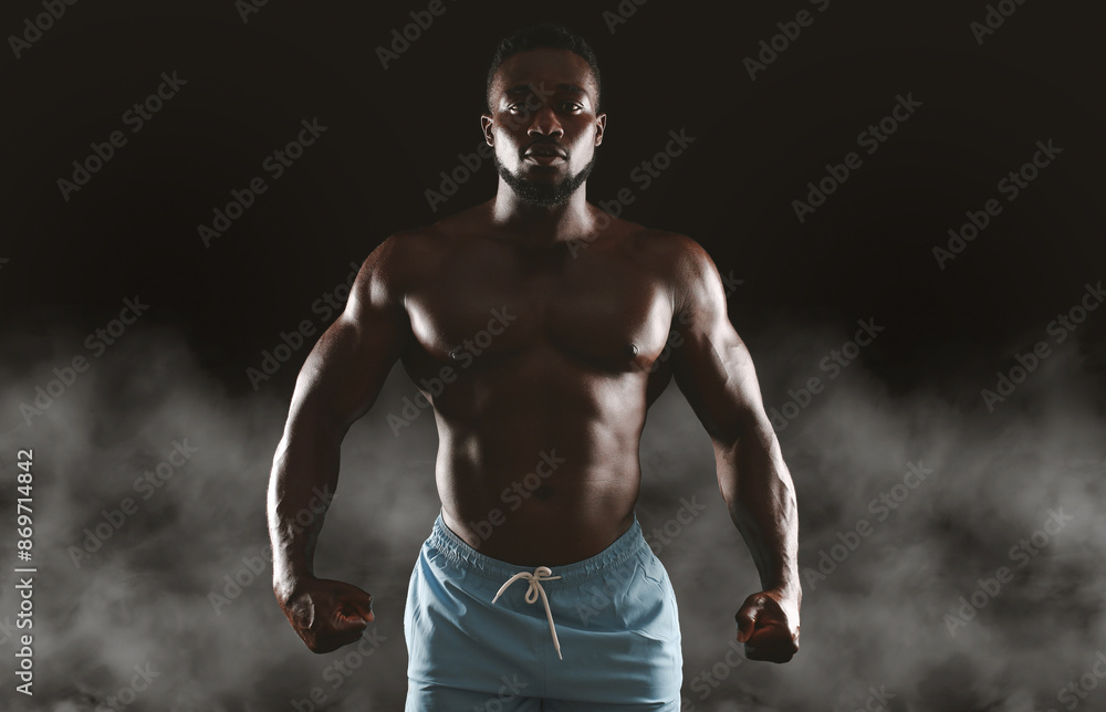 custom made wallpaper toronto digitalA muscular man stands with his fists clenched, posing in front of a dark background with smoke.