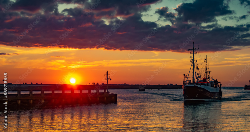 a ship entering the port at sunset in Ustka a ship entering the port at sunset in Ustka
