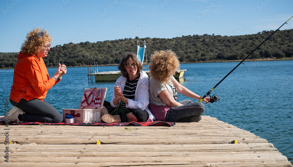 Middle-aged sisters fishing and relaxing by the lagoon Middle-aged sisters fishing and relaxing by the lagoon