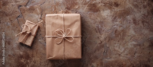 Top view of a gift box adorned in brown recycled paper, tied with a rope bag, set against a backdrop with copy space image. photo