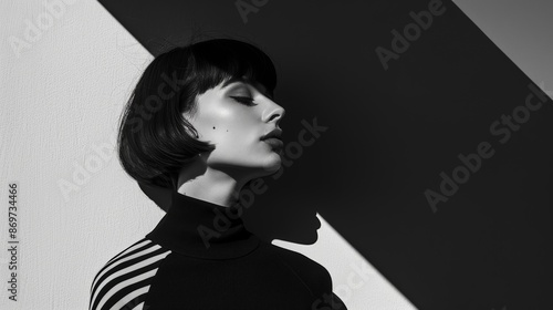 man in black clothes on a monochrome background. Black and white photo - Portrait of a beautiful young woman dressed in all black on a minimalistic background