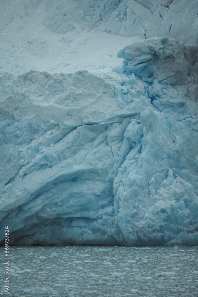 Antarctica Glacier Ice Shelf. Details Blue and White Snow. Icebergs Scattered in the Water Below View From Boat. Climate Change Global Warming.