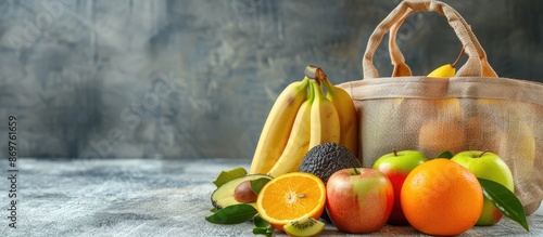 Fototapeta Naklejka Na Ścianę i Meble -  Various fruits like bananas, apples, oranges, and avocado displayed on a table with an eco bag in the background for a copy space image.