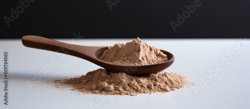 A plastic measuring spoon holds whey chocolate protein powder on a dark wooden board against a white backdrop with copy space image. photo