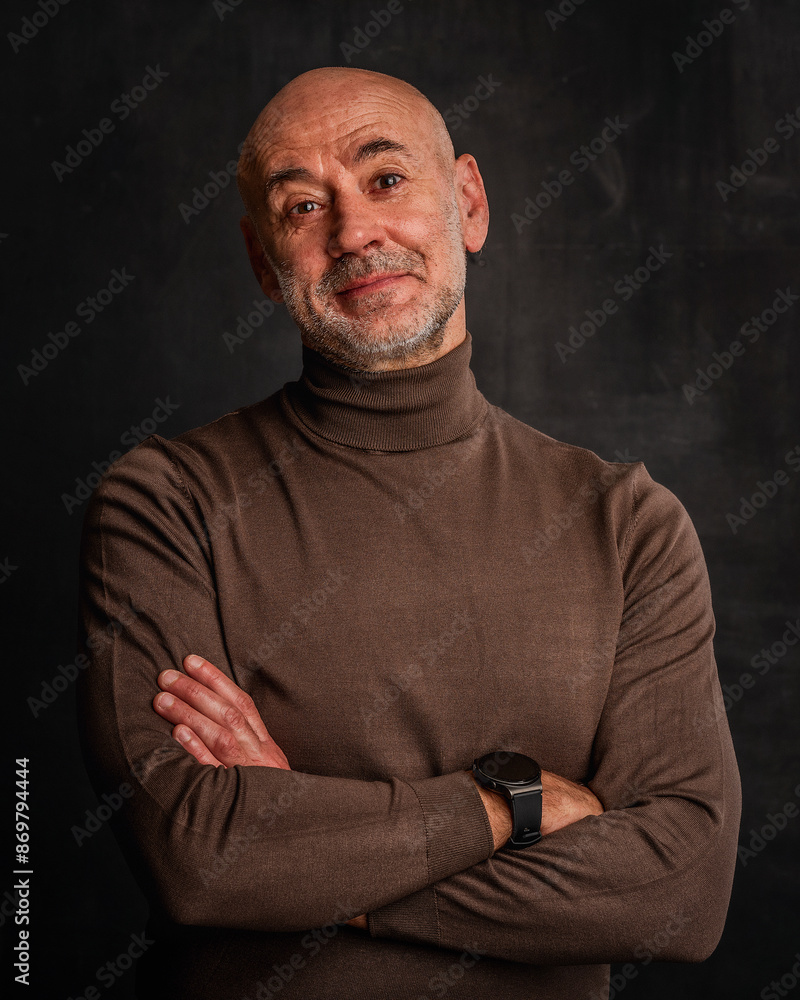Obraz premium Close-up portrait of a mid aged man sitting against isolated dark background