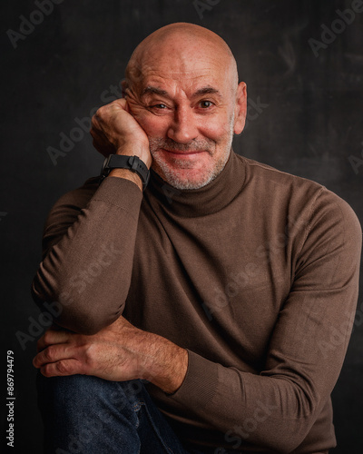 Close-up portrait of a mid aged man sitting against isolated dark background