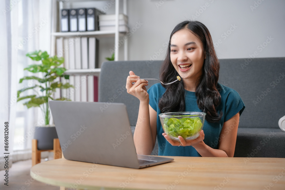 Young woman eating salad and having video call using laptop at home Young woman eating salad and having video call using laptop at home