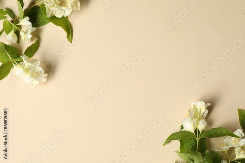 Fototapeta Naklejka Na Ścianę i Meble -  Aromatic jasmine flowers and green leaves on beige background, flat lay. Space for text