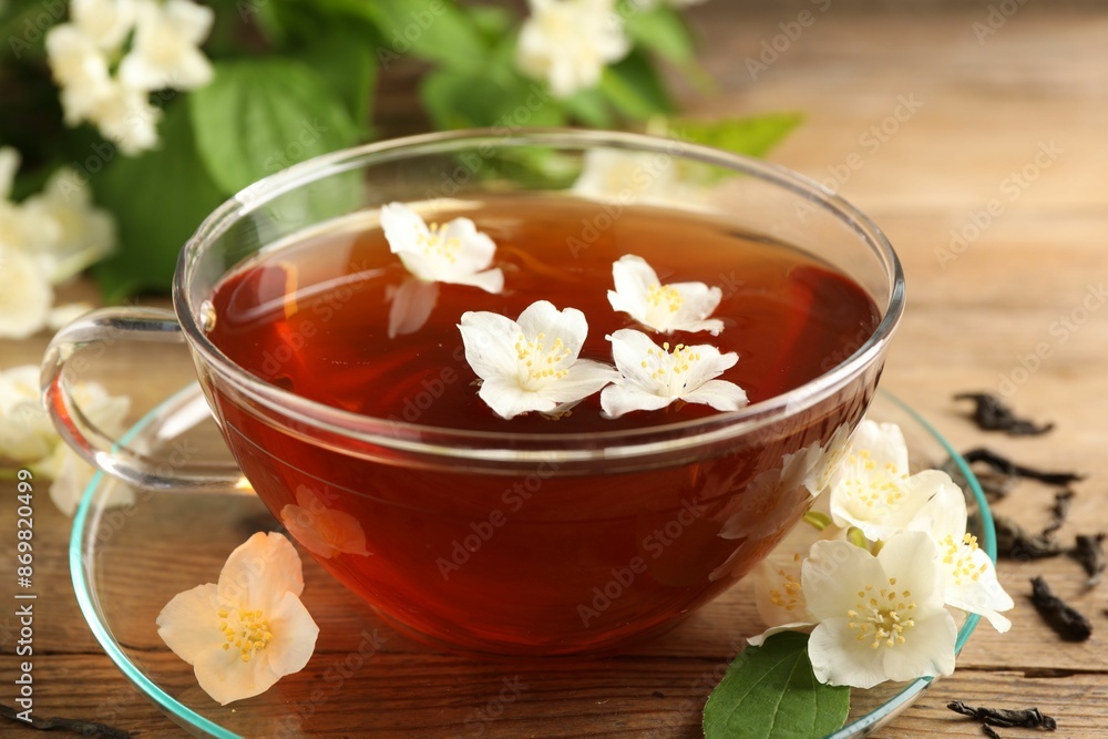 Hot jasmine tea in cup and flowers on wooden table, closeup Hot jasmine tea in cup and flowers on wooden table, closeup