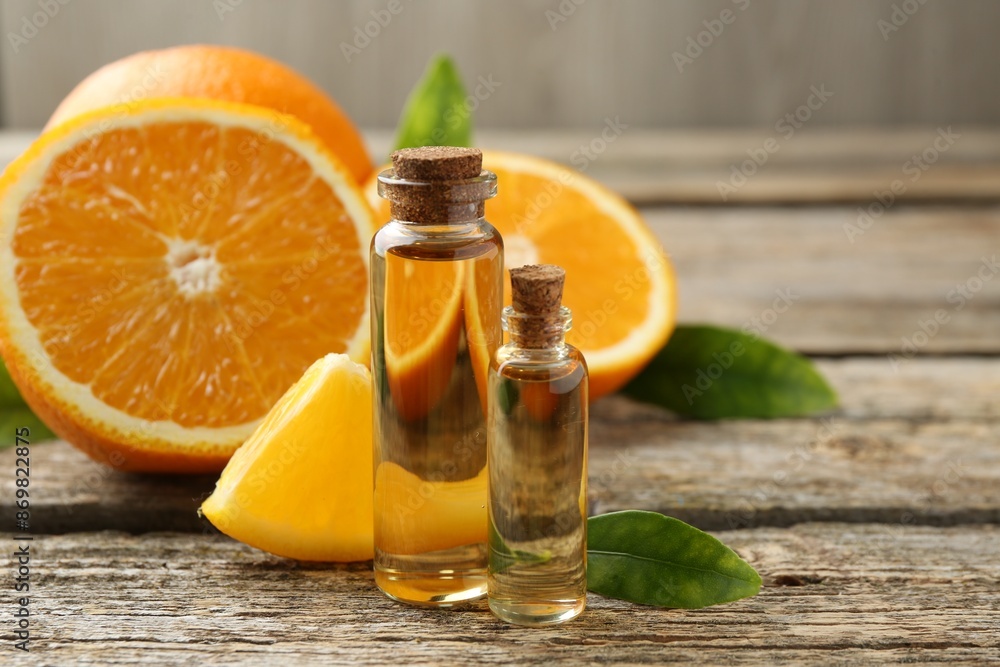 Essential oils in bottles, oranges and green leaves on wooden table Essential oils in bottles, oranges and green leaves on wooden table