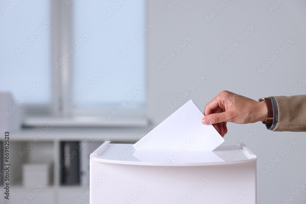 Woman putting her vote into ballot box indoors, closeup Woman putting her vote into ballot box indoors, closeup