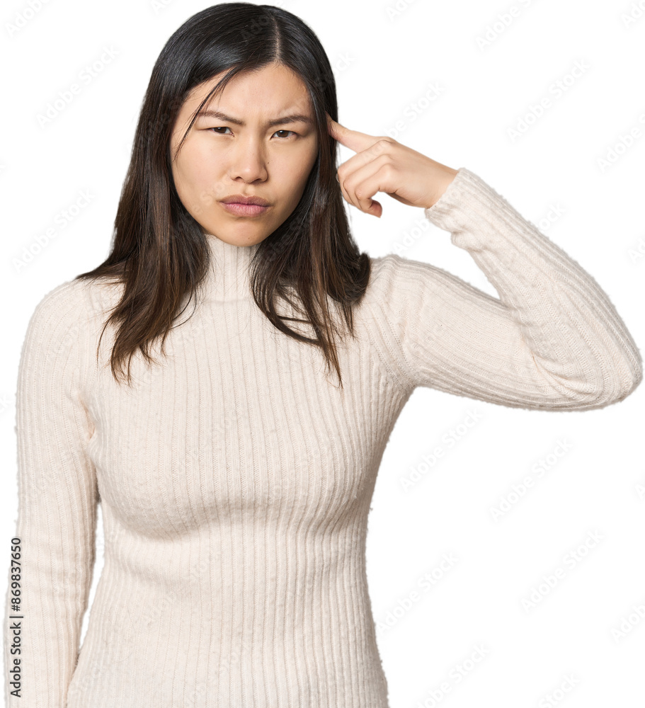 Young Chinese woman pointing temple with finger, thinking, focused on a task. Young Chinese woman pointing temple with finger, thinking, focused on a task.