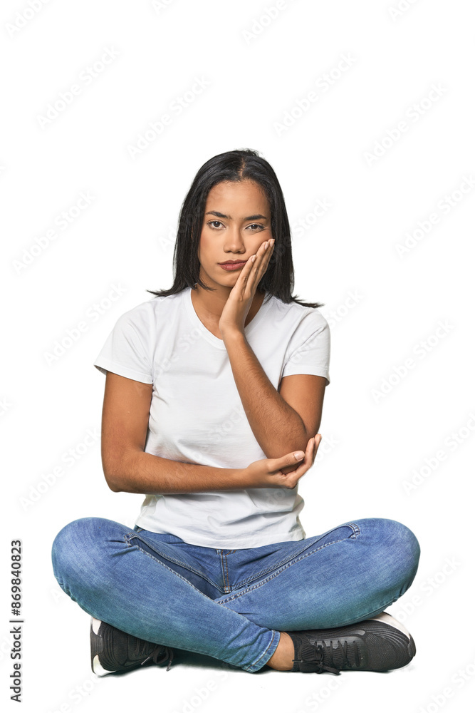 Latina sitting on floor in studio who is bored, fatigued and need a relax day. Latina sitting on floor in studio who is bored, fatigued and need a relax day.