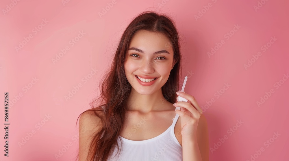 Young woman showing a positive pregnancy test in front of a pink background, expressing joy, waist-up photo Young woman showing a positive pregnancy test in front of a pink background, expressing joy, waist-up photo
