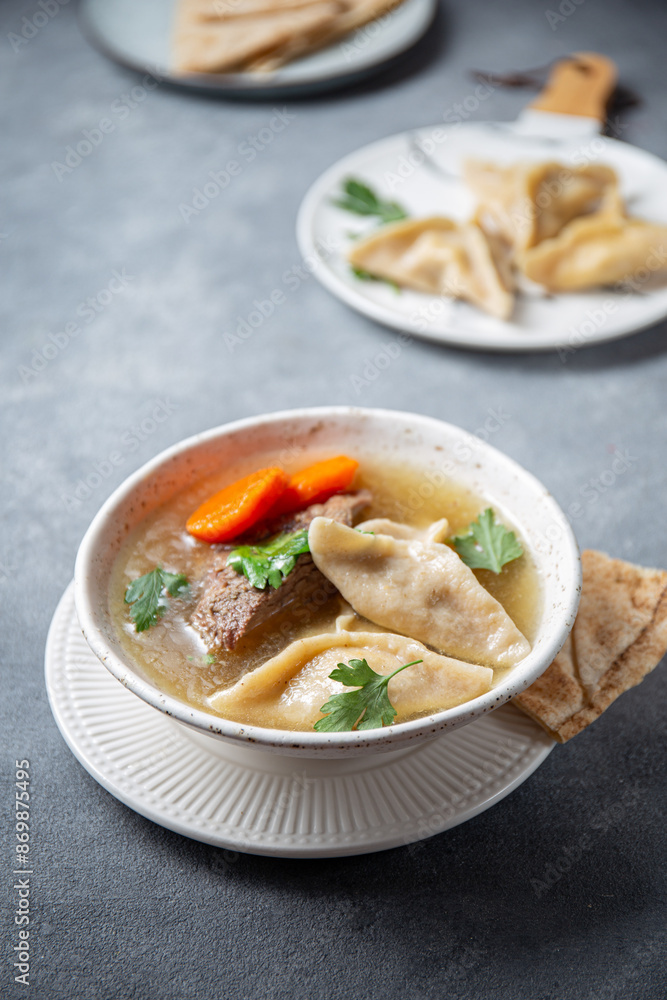 Traditional Jewish Kreplach soup with meat and carrot, gray background Traditional Jewish Kreplach soup with meat and carrot, gray background