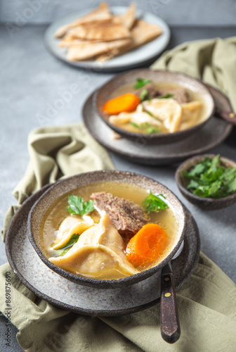 Traditional Jewish Kreplach soup with meat and carrot, gray background photo