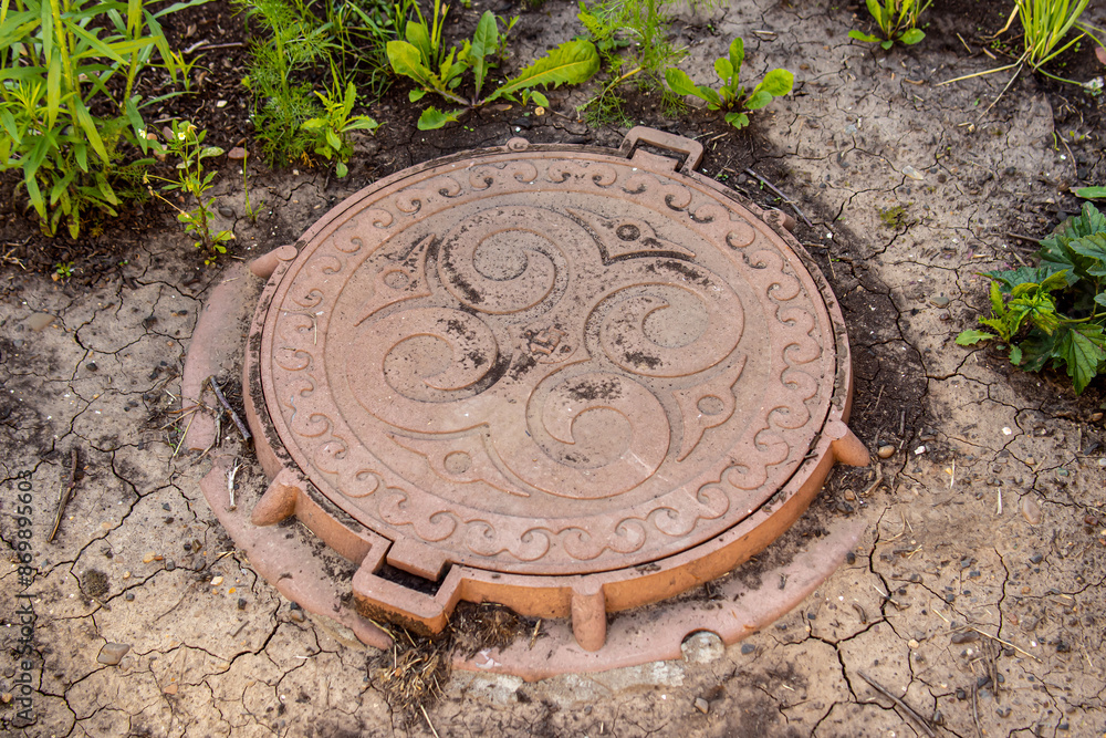 Manhole or well in the garden. Sewerage in country house. Metal well cover Manhole or well in the garden. Sewerage in country house. Metal well cover