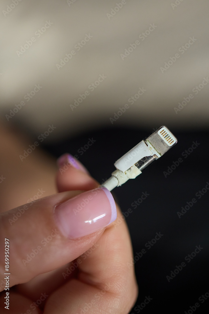 The image shows a closeup of someone gripping a lightning cable that appears to be damaged The image shows a closeup of someone gripping a lightning cable that appears to be damaged