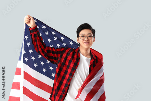 Young Asian man with USA flag on light background