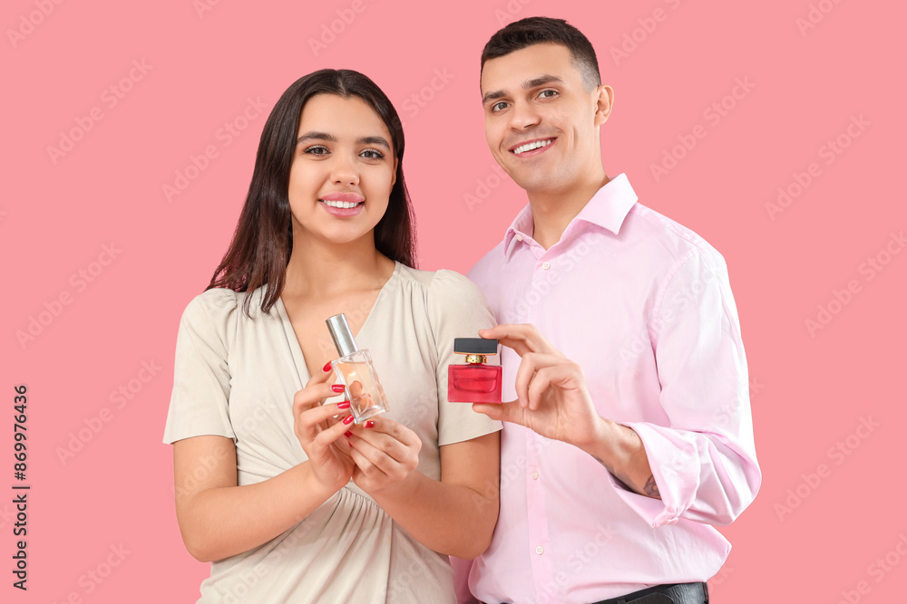 Young couple with bottles of perfume on pink background Young couple with bottles of perfume on pink background