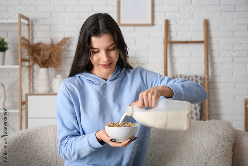 Young woman pouring milk in...