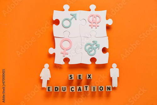 Cubes with text SEX EDUCATION, puzzle pieces, human figures, female and male symbols on orange background