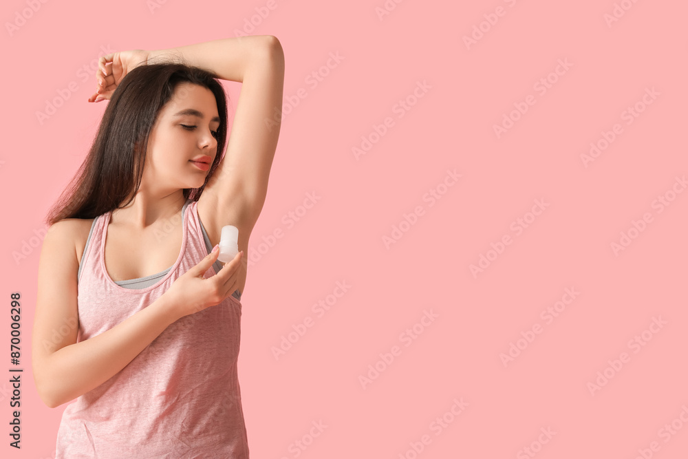 Beautiful young woman using crystal deodorant on pink background Beautiful young woman using crystal deodorant on pink background