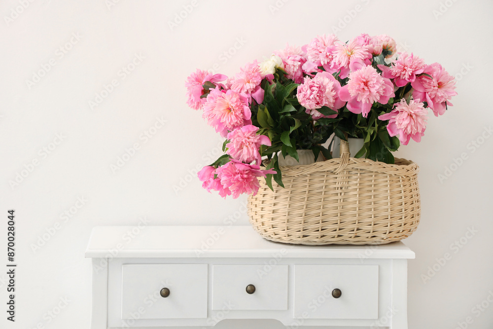 Wicker basket with peony flowers on toilet table in room Wicker basket with peony flowers on toilet table in room