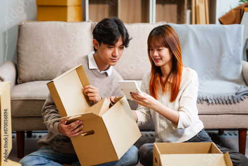 Young women, men, and Asian people prepare for moving into a new home. From unpacking supplies to updating documents, follow a comprehensive checklist in the living room with a big cardboard box.