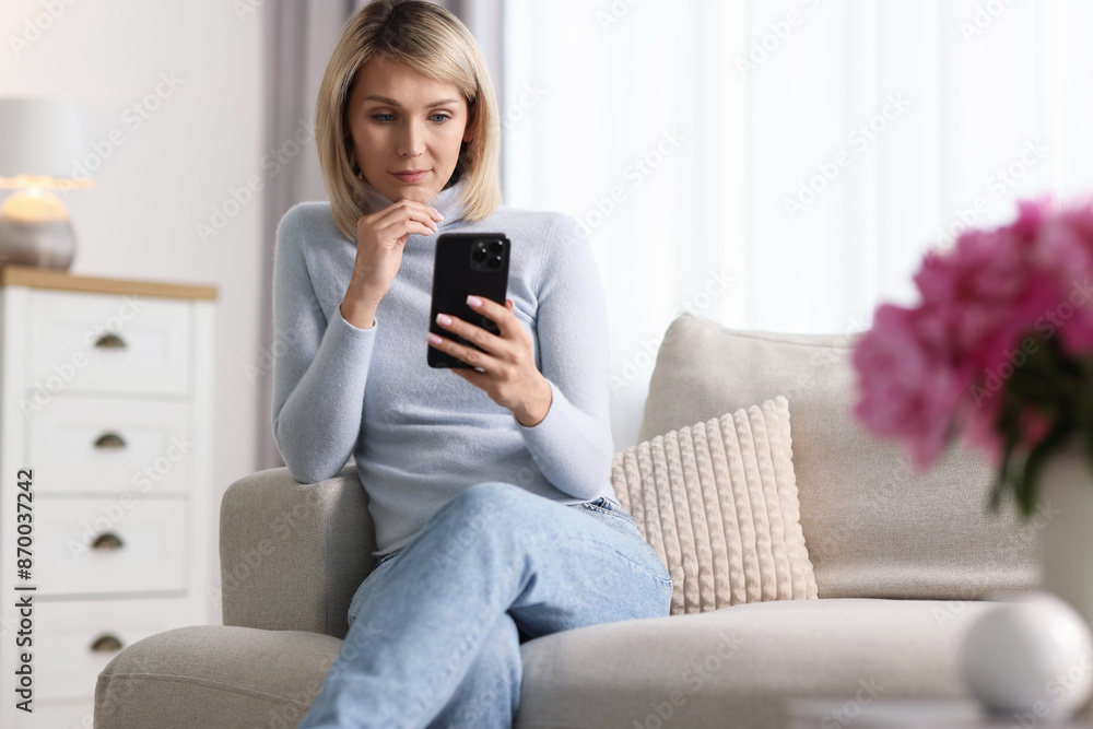 Woman using mobile phone on sofa at home Woman using mobile phone on sofa at home
