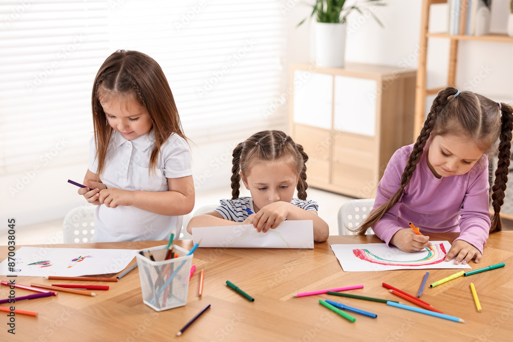 Cute little children drawing at wooden table indoors Cute little children drawing at wooden table indoors