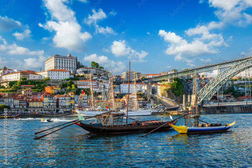Obraz premium View of Porto city and Douro river with traditional boats with port wine barrels and sailing ship from famous tourist viewpoint Marginal de Gaia riverfront. Porto, Vila Nova de Gaia, Portugal